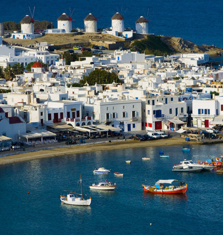 Traditional windmills and whitewashed houses by the sea in Mykonos, Greece.